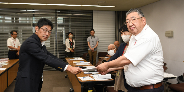 厚労省職員に要望書を手渡す関口直久桐生市議会議員（右）ら（8月6日 都内／榎園哲哉）